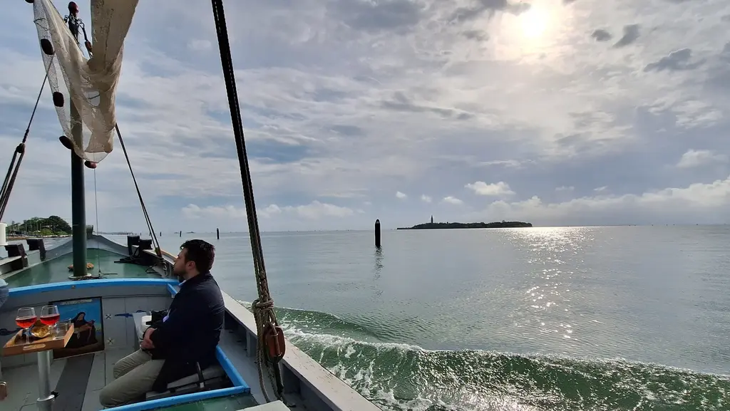 Cruising with Stella, a classic Bragozzo, along Lido during Sunset with a view of Poveglia Island.